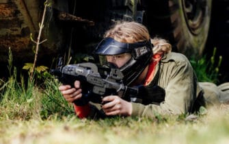 dame ligt in gras met airsoft gun