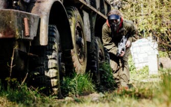 airsoft speler loopt langs wagen met grote banden