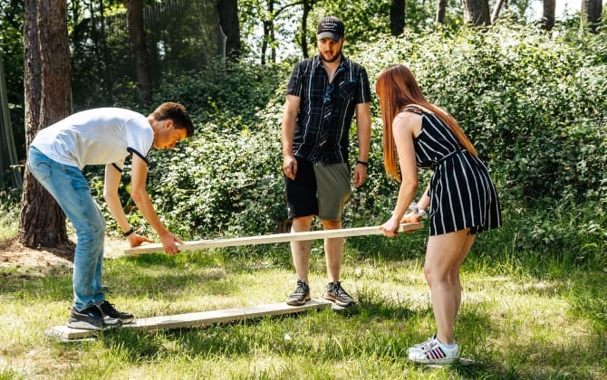 twee mensen houden balk man staat achter