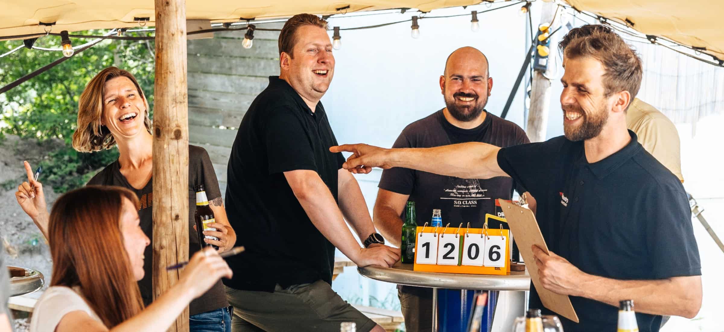 Pubquiz vrijgezellenfeest pub quiz leider wijst aan team gezellig op achtergrond met score